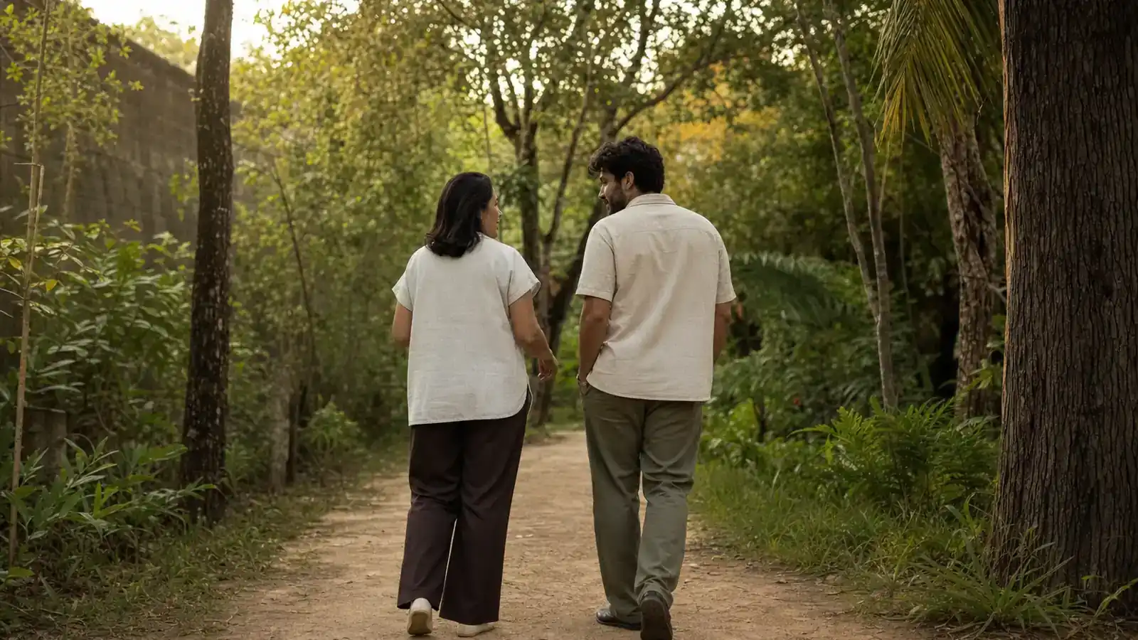 Duas pessoas caminhando e conversando em uma trilha arborizada