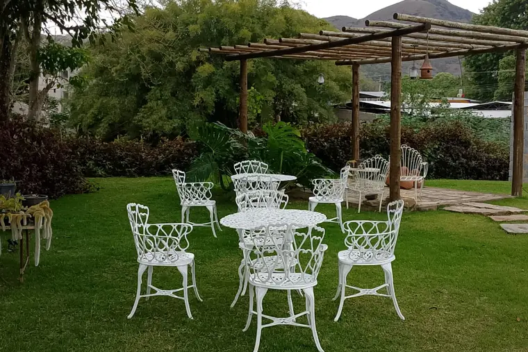 Jardim com mesas e cadeiras brancas, em unidade de acolhimento da rede em Minas Gerais