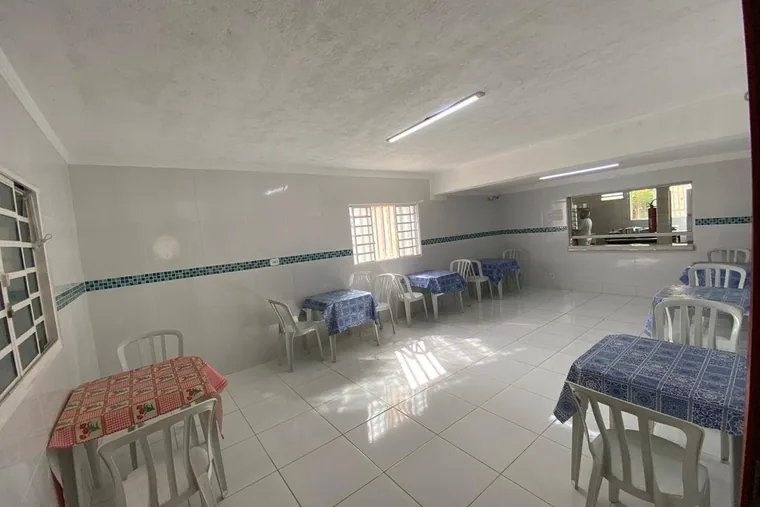 Sala com mesas e cadeiras brancas, em unidade de acolhimento da rede em Minas Gerais