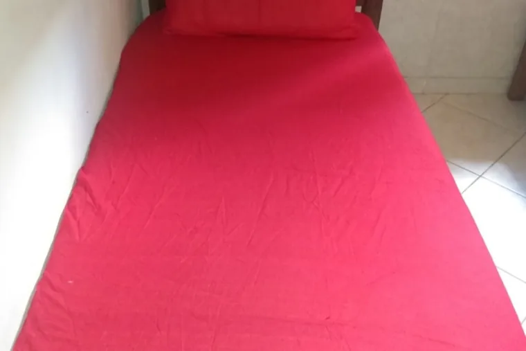 Cama com lençol vermelho, em unidade de acolhimento da rede em Minas Gerais