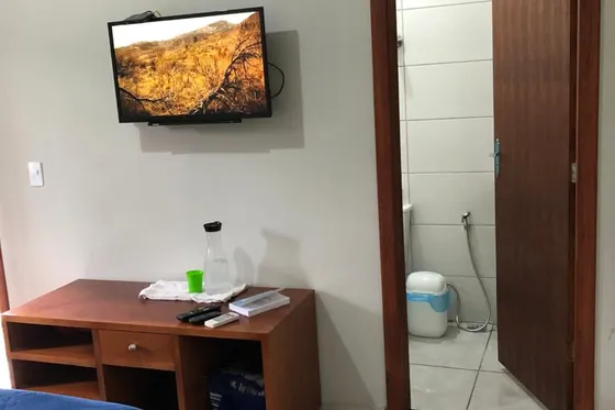 Quarto com TV e banheiro ao fundo