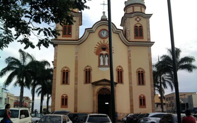 Igreja com árvores e carros estacionados em Alfenas