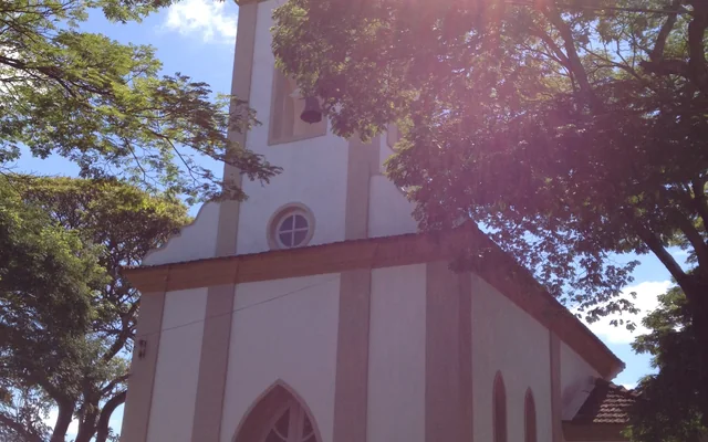 Igreja rodeada por árvores e céu azul em Carmópolis de Minas